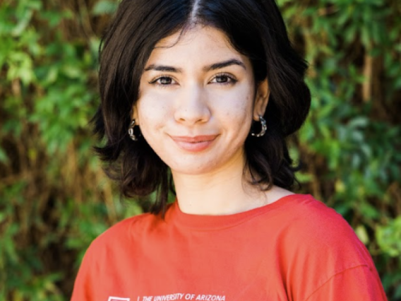 photo of a person in a red University of Arizona t shirt in front of green hedgerows