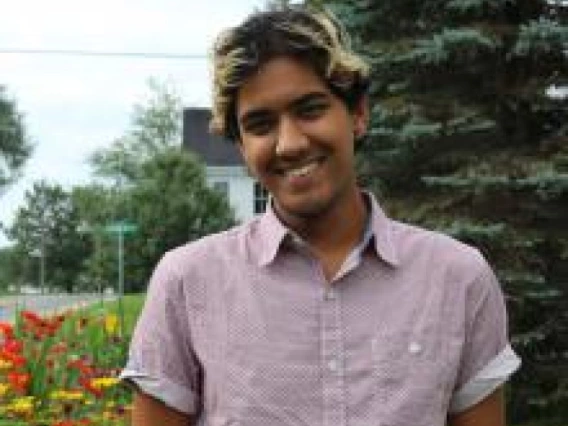 a photo of a person in a pink button-up shirt in front of a tree and flowers