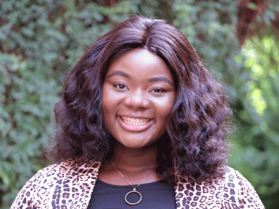 Picture of a person wearing a leopard-print blouse in front of a courtyard and greenery