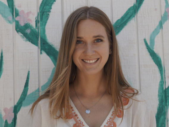 photo of a person in front of a white panel wall painted with flowers