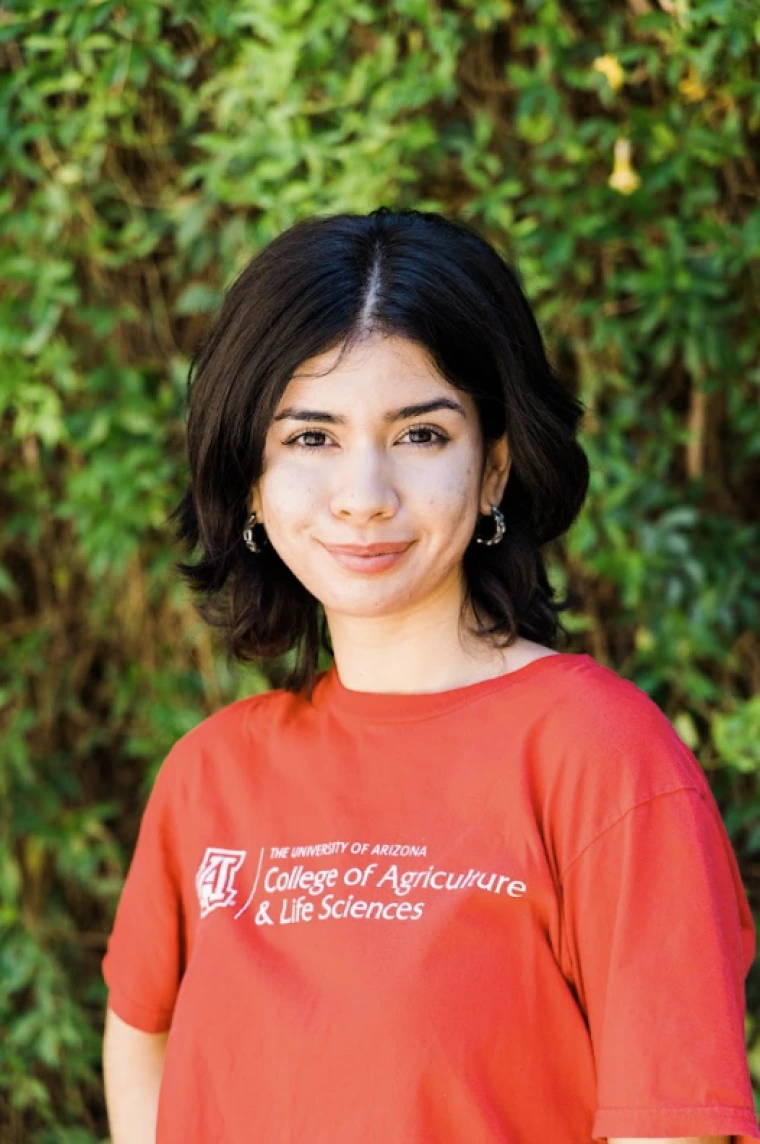 photo of a person in a red University of Arizona t shirt in front of green hedgerows