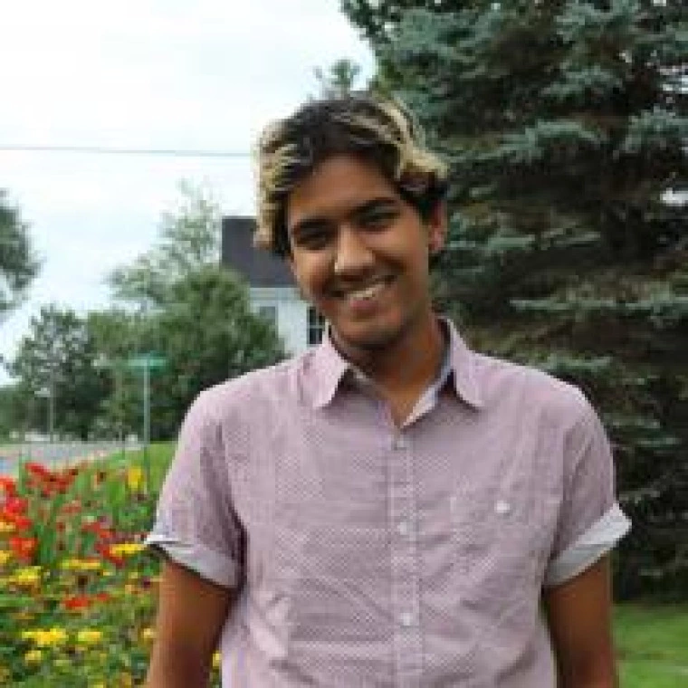 a photo of a person in a pink button-up shirt in front of a tree and flowers