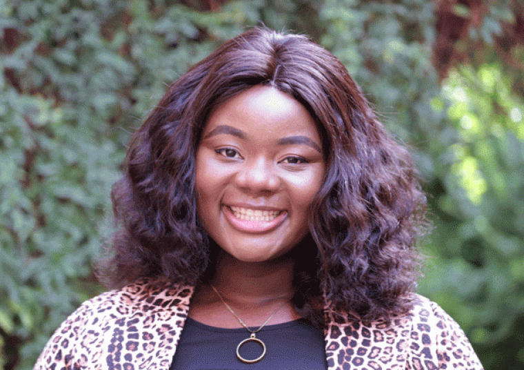 Picture of a person wearing a leopard-print blouse in front of a courtyard and greenery