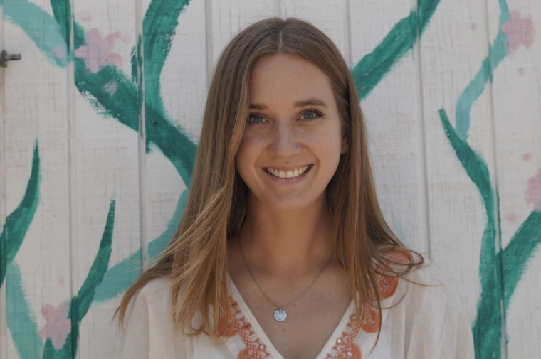 photo of a person in front of a white panel wall painted with flowers